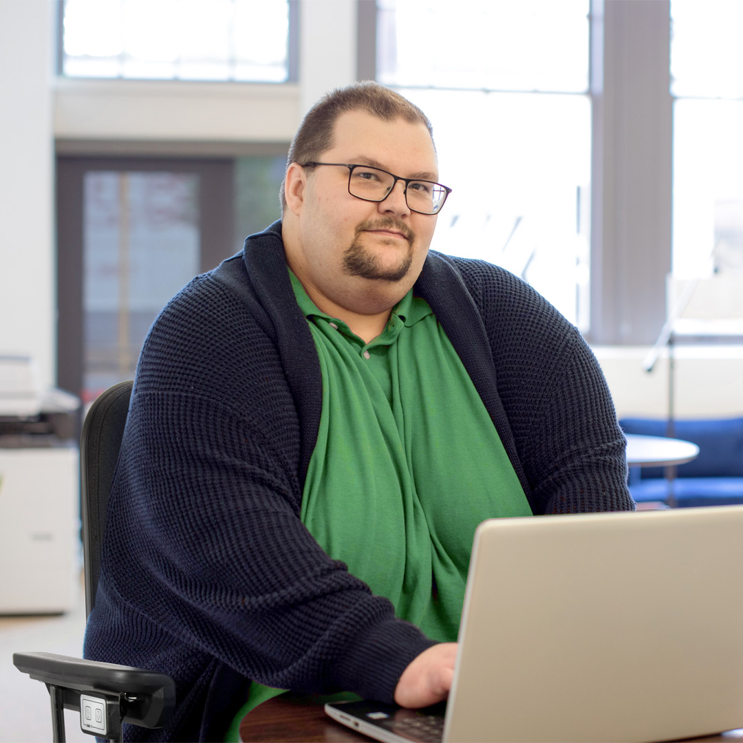 Ein Mensch mit Übergewicht nutzt einen stabilen und breiten Bürostuhl mit Höhenverstellung